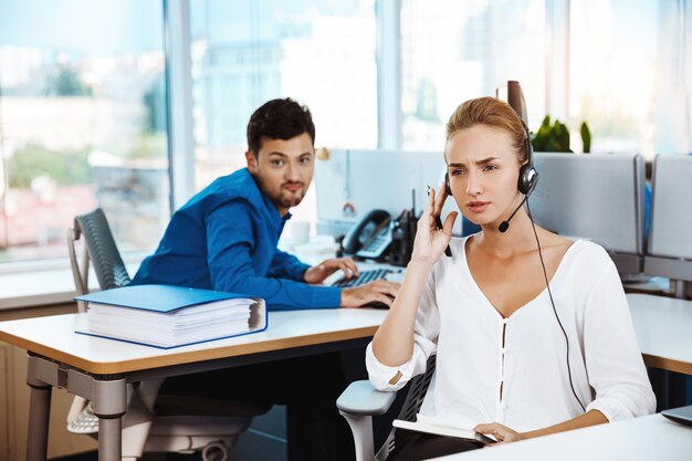 Het jonge mooie vrouwelijke exploitant van de steuntelefoon spreken, die over bureau raadplegen