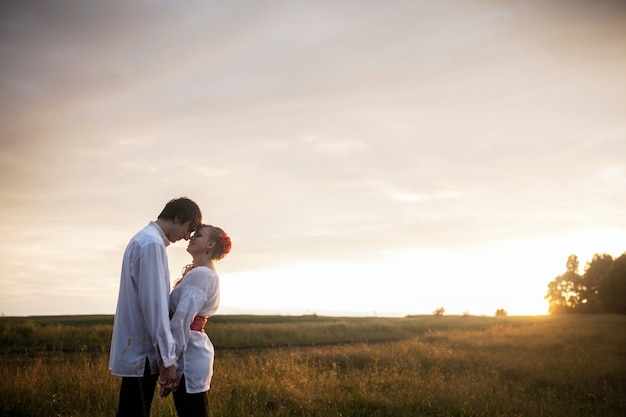 Het jonge paar flirten in de weide bij zonsondergang