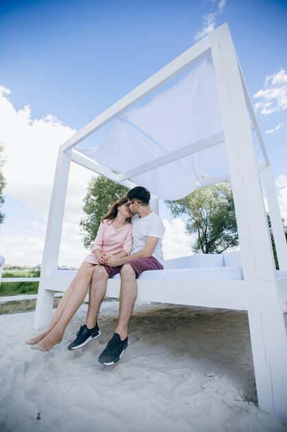 Het jonge paar kussen op een bed op het strand