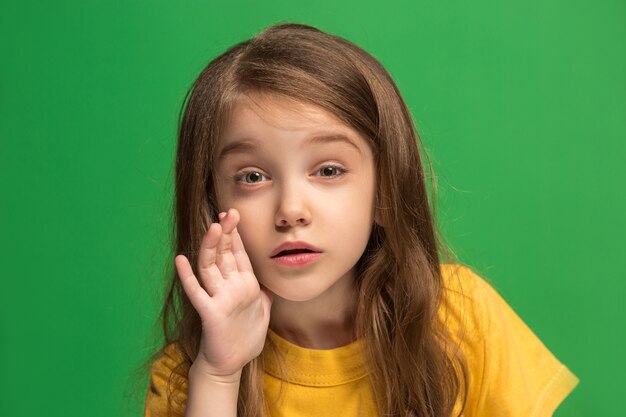 Het jonge tienermeisje dat een geheim achter haar fluistert hand over groene achtergrond