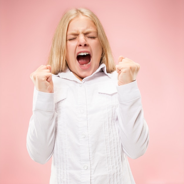 Het jonge toevallige tienermeisje schreeuwen. roepen. huilende emotionele tiener die op roze ruimte gilt. vrouwelijke halve lengte portret