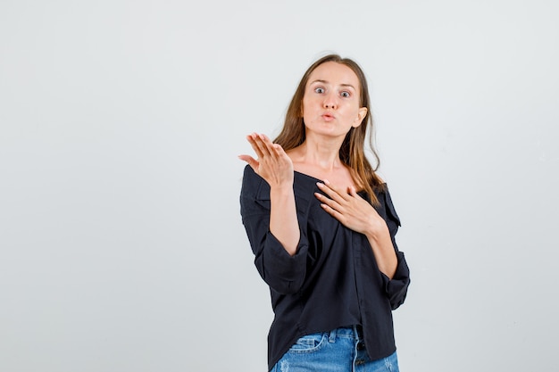 Het jonge vrouw opheffen dient overhemd, borrels in en kijkt boos. vooraanzicht.