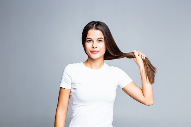 Het jonge vrouw raken en speelt met haar haar dat op wit wordt geïsoleerd