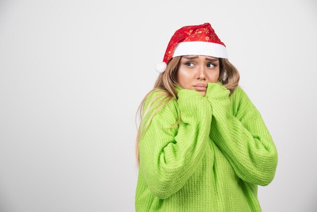 Gratis foto het jonge vrouw stellen in de rode hoed van de kerstman.