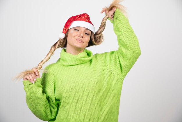 Het jonge vrouw stellen in de rode hoed van de Kerstman.