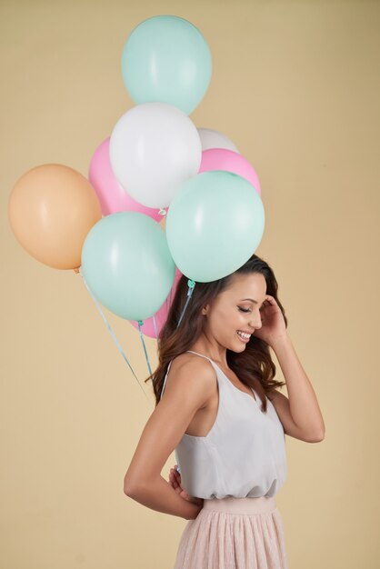 Het jonge vrouw stellen in studio met bos van kleurrijke helium baloons