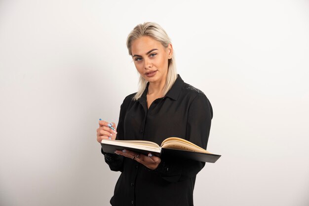 Het jonge vrouw stellen met een kop en een klembord op witte achtergrond. Hoge kwaliteit foto