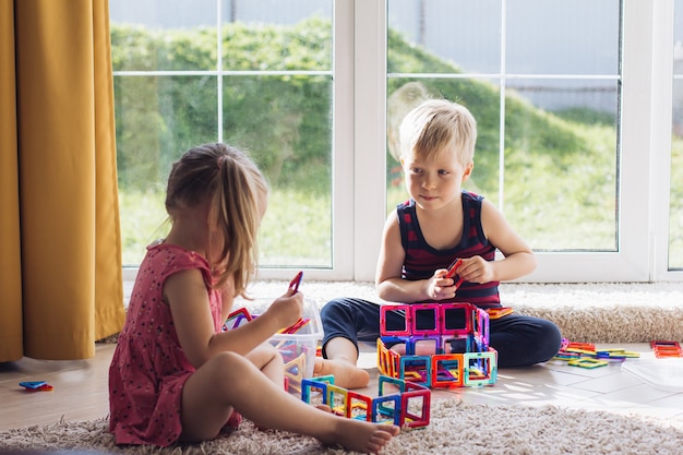 Het kind speelt met een veelkleurige magnetische constructor en bouwt een toren. educatief speelgoed voor kleine kinderen. een bouwsteen voor een baby of peuter rommel in de speelkamer