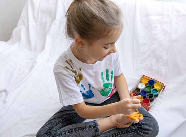 Het kind tekent met een penseel een patroon op zijn voet.