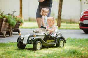 Gratis foto het kleine babymeisje dat bij auto speelt