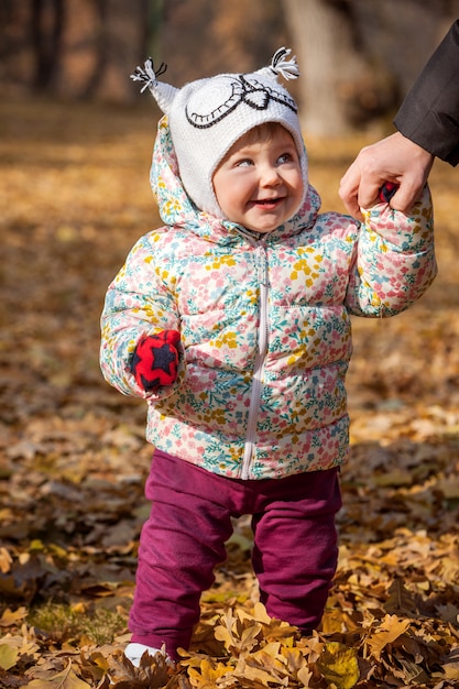 Gratis foto het kleine babymeisje dat zich in de herfstbladeren bevindt