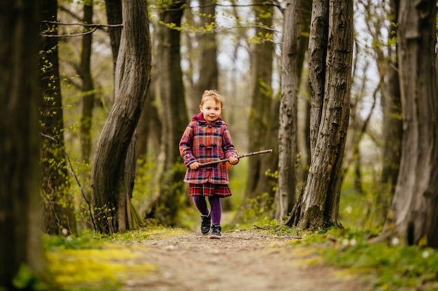 Het kleine kind dat een boomstam houdt en langs park loopt
