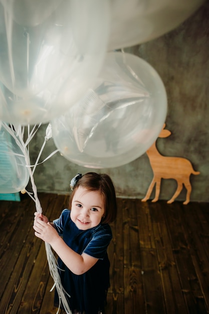 Het kleine meisje houdt ballons in de kamer