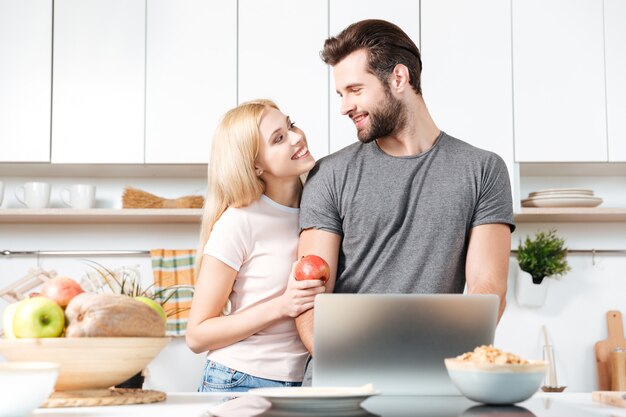 Het koken van het paar in keuken met laptop computer