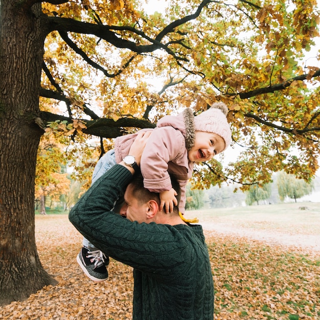 Het lachen kind en papa het spelen in de herfstpark