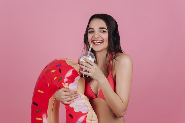 Het lachende meisje in strandkleding bevindt zich met een cocktail en de grote doughnut zwemt ring