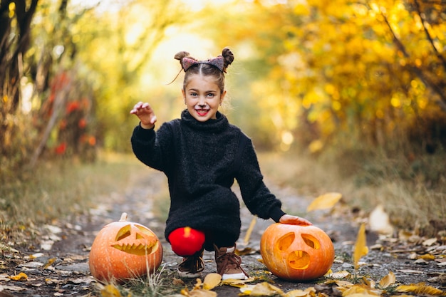 Het leuke meisje kleedde zich in openlucht in Halloween-kostuum met pompoenen
