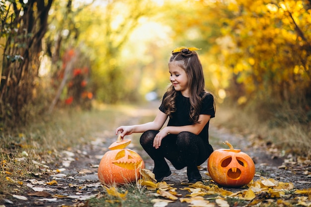 Het leuke meisje kleedde zich in openlucht in Halloween-kostuum met pompoenen