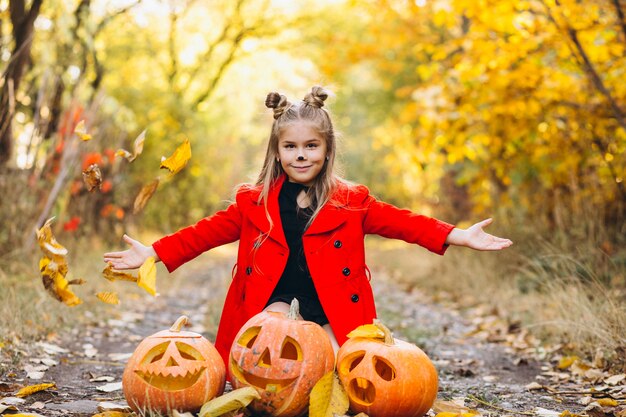 Het leuke meisje kleedde zich in openlucht in Halloween-kostuum met pompoenen