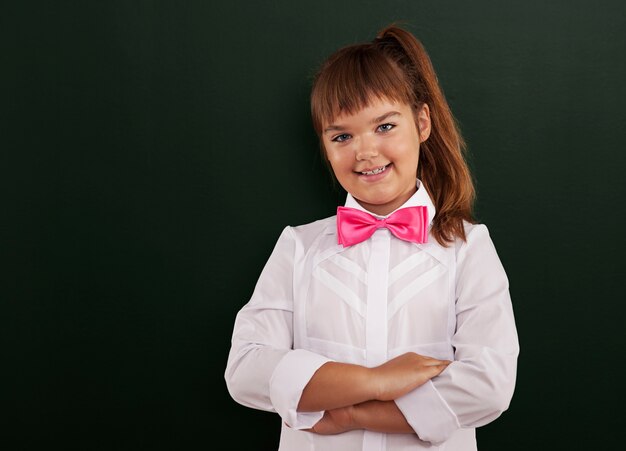 Het leuke schoolmeisje stellen voor bord