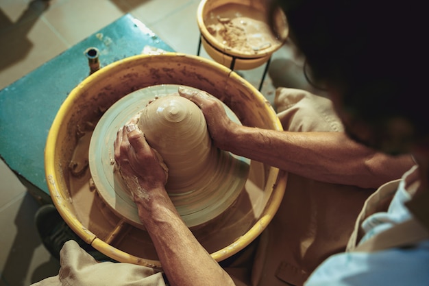 Gratis foto het maken van een pot of vaas van witte klei close-up. meesterpot.