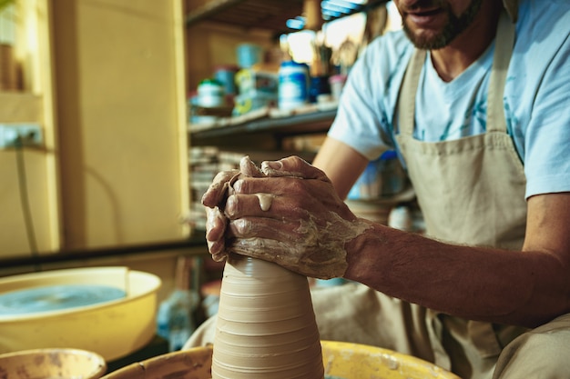 Gratis foto het maken van een pot of vaas van witte klei close-up. meesterpot.