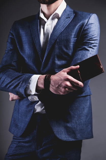 Het manierportret van de jonge zakenman knappe modelmens kleedde zich in elegant blauw kostuum op grijs.