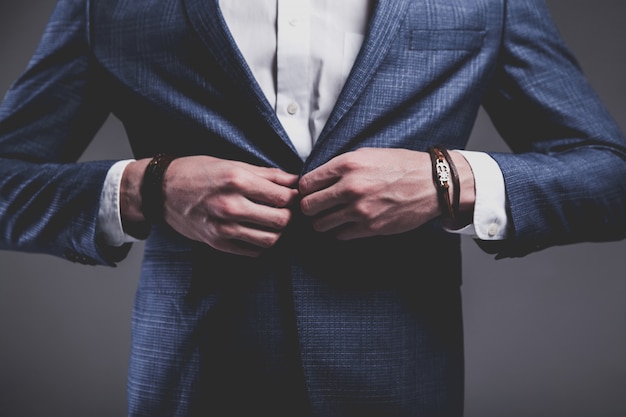 Het manierportret van de jonge zakenman knappe modelmens kleedde zich in elegant blauw kostuum op grijs.