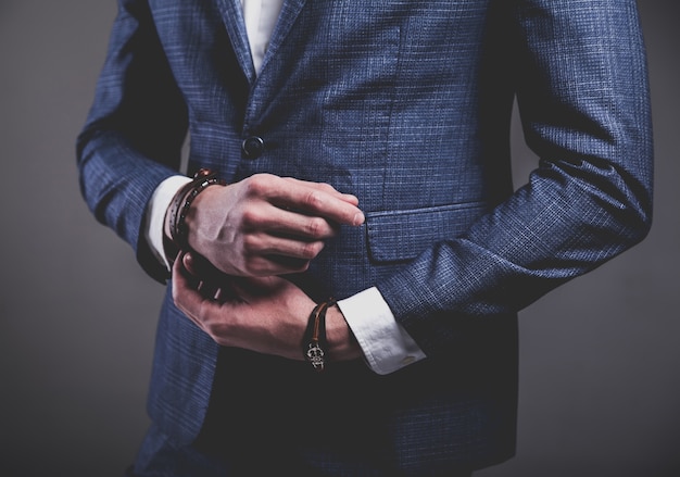 Het manierportret van de jonge zakenman knappe modelmens kleedde zich in elegant blauw kostuum op grijs.