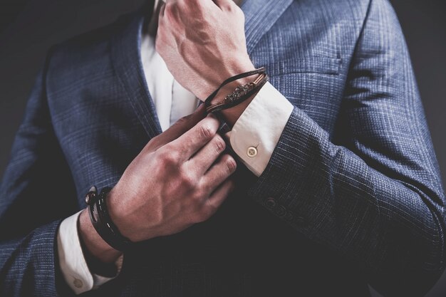 Het manierportret van de jonge zakenman knappe modelmens kleedde zich in elegant blauw kostuum op grijs.