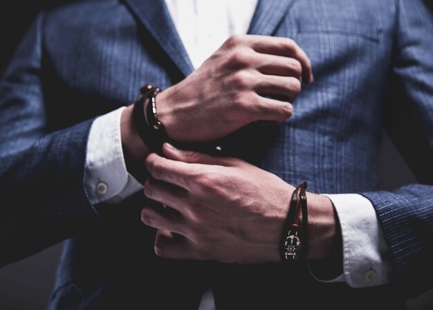 Het manierportret van de jonge zakenman knappe modelmens kleedde zich in elegant blauw kostuum op grijs.