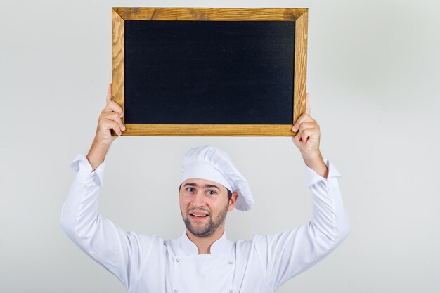 Het mannelijke bord boven het hoofd van de chef-kok in wit uniform en op zoek positief.