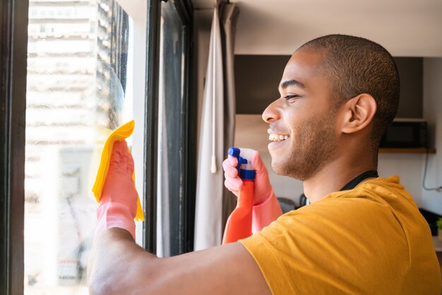 Het mannelijke venster van het huishoudster schoonmakende glas thuis.