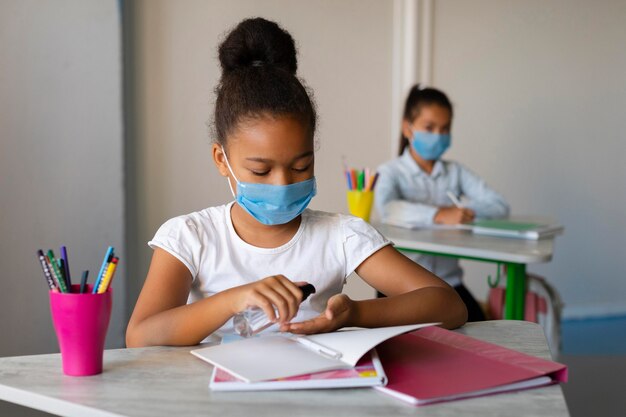 Het meisje dat haar handen desinfecteert in de klas