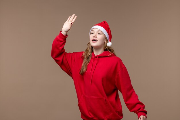 Het meisje dat van vooraanzichtkerstmis en op bruine achtergrondvakantie modelkerstmis golven groet