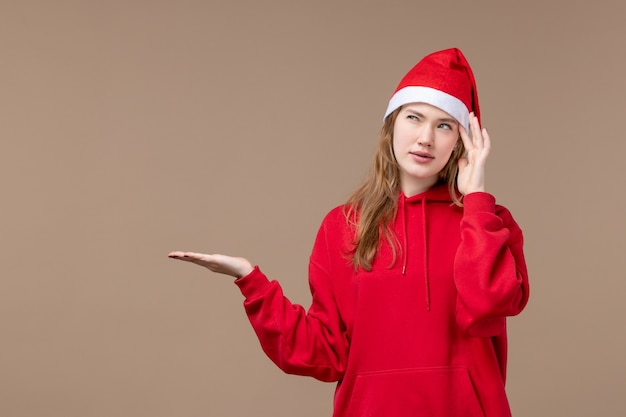 Gratis foto het meisje die van vooraanzichtkerstmis op de bruine kerstmis van het achtergrondvakantie nieuwe jaar denken