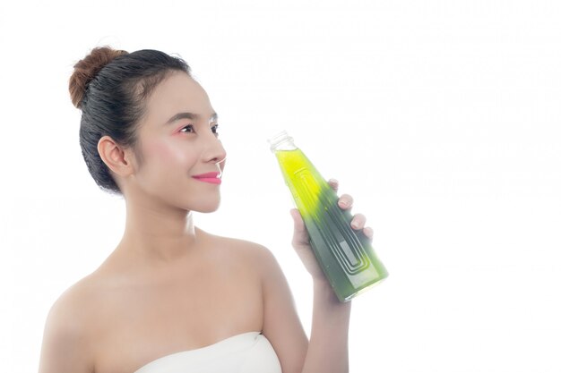 Het meisje drinkt groen water op een witte achtergrond.