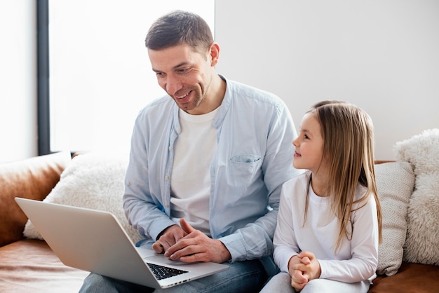 Het meisje en haar vader brengen tijd door op laptop