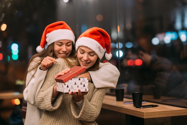 Het meisje geeft een cadeau aan haar vriendin in het café