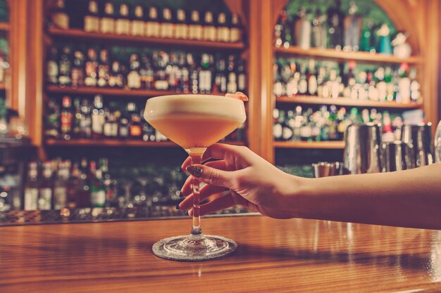 Het meisje houdt in zijn hand een glas alcoholische drank aan de bar