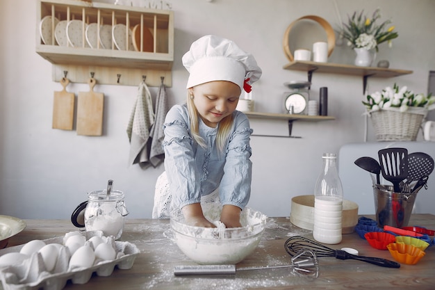 Het meisje in een witte shefhoed kookt het deeg voor koekjes