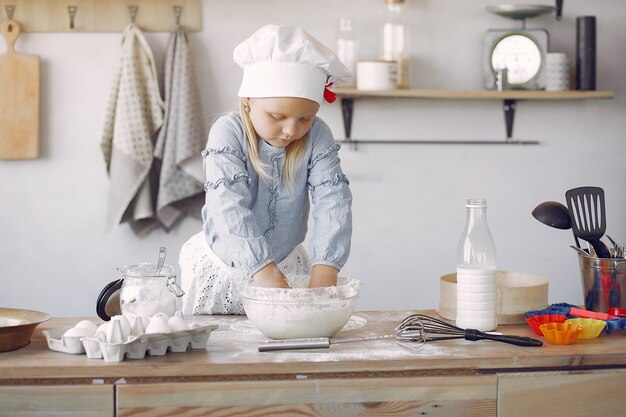 Het meisje in een witte shefhoed kookt het deeg voor koekjes