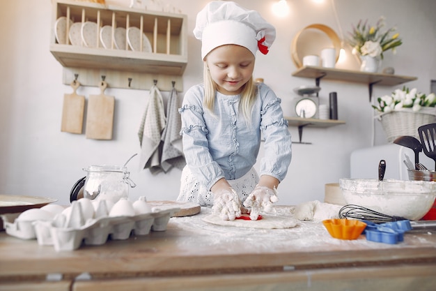 Het meisje in een witte shefhoed kookt het deeg voor koekjes