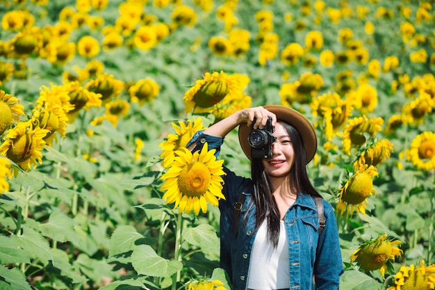 Het meisje neemt graag foto&#39;s in het zonnebloemveld.