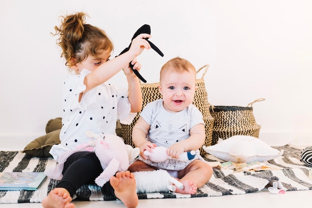 Het meisje probeert om hoofdband op baby te zetten