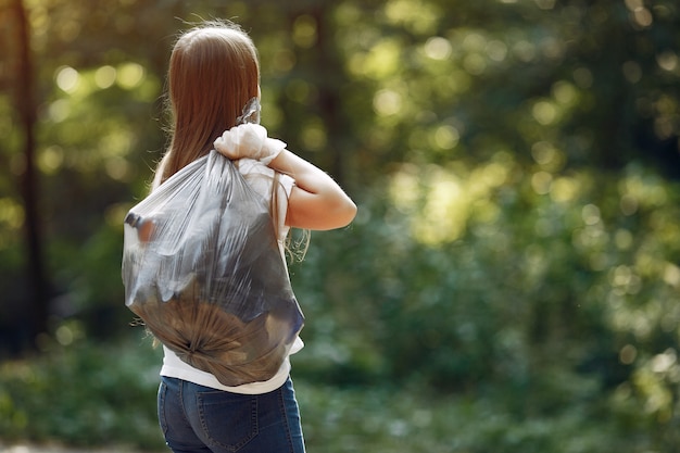 Het meisje verzamelt afval in vuilniszakken in park