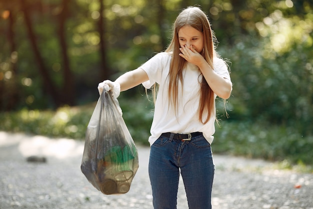 Het meisje verzamelt afval in vuilniszakken in park