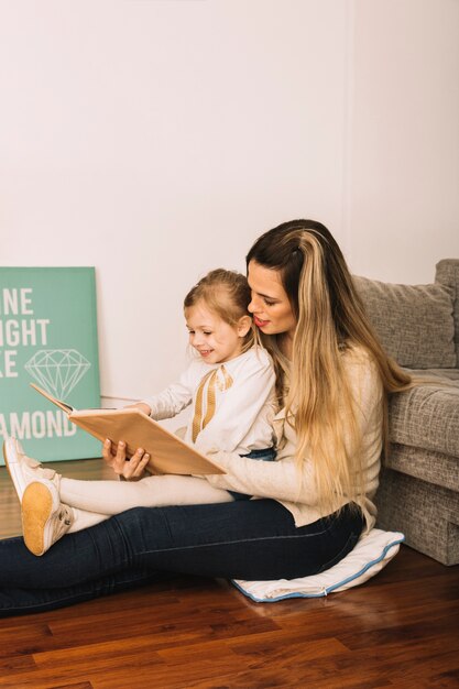 Het mooie boek van de vrouwenlezing met dochter op vloer