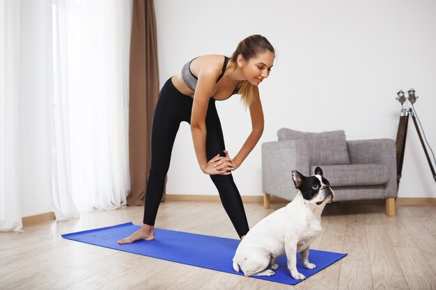 Het mooie fitness meisje maakt sportoefeningen met hond