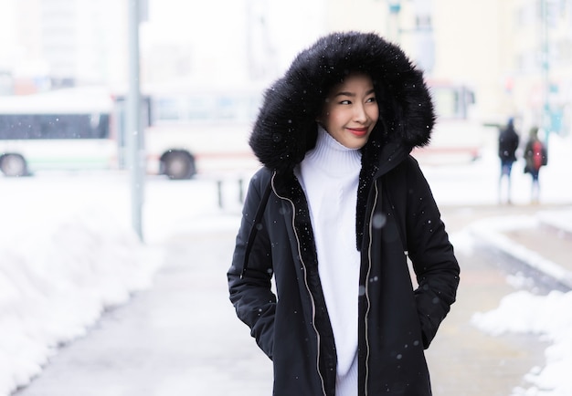Het mooie jonge aziatische vrouw glimlachen gelukkig voor reis in sneeuw wintertijd